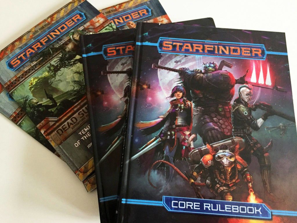 A pack of Starfinder RPG rulebooks and campaign books on our desk.